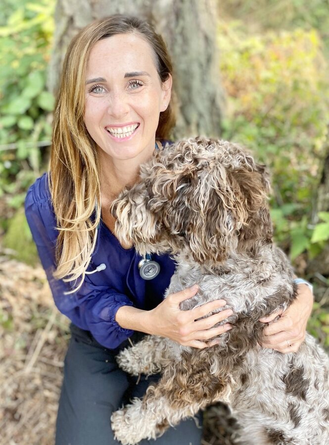 Dr. Elyse Macartney, DVM, holding a curly-coated dog